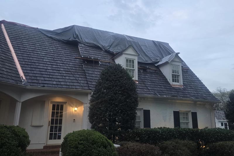 a home at dusk that is tarped due to roof storm damage