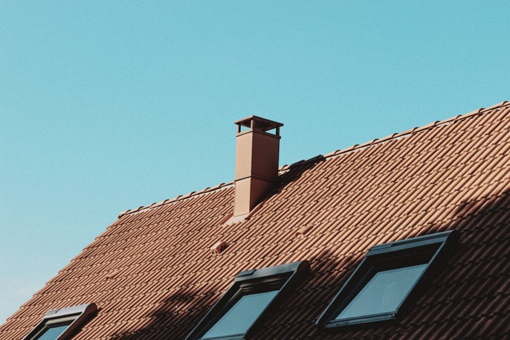 contemporary house roof with chimney under a clear blue sky