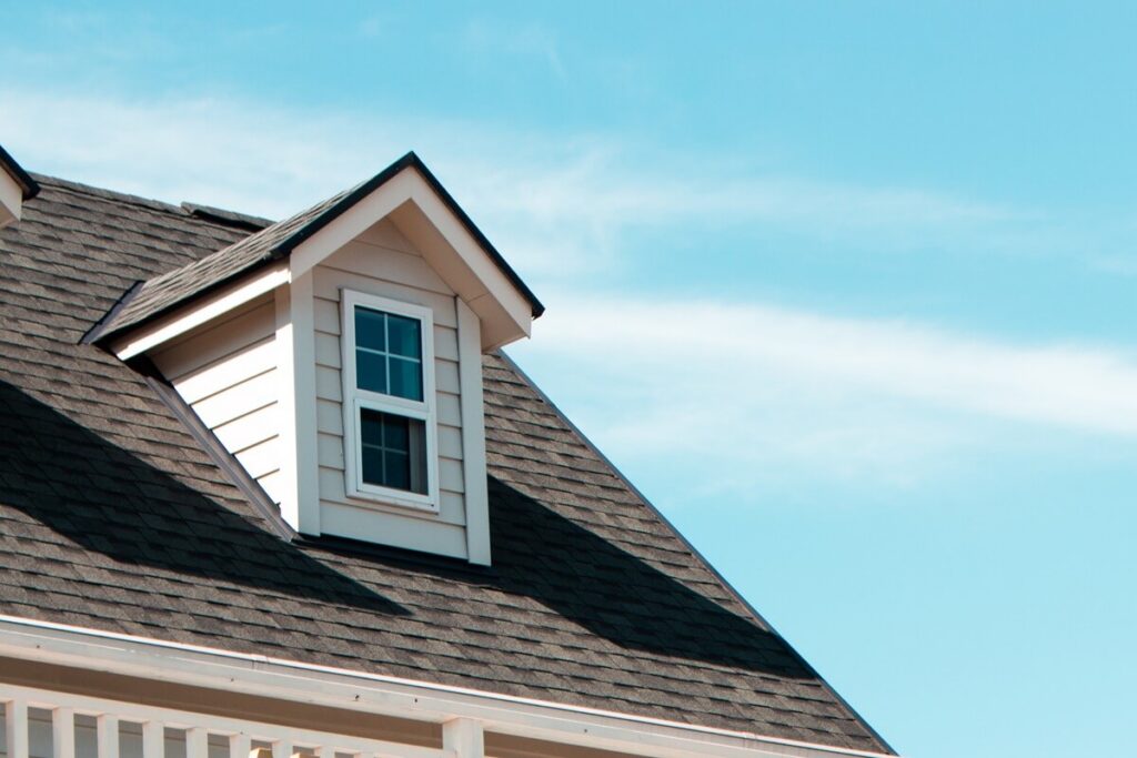 image of authentic European house roof and roof window in blue sky with cloud