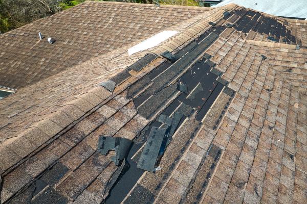 Damaged house roof with missing shingles