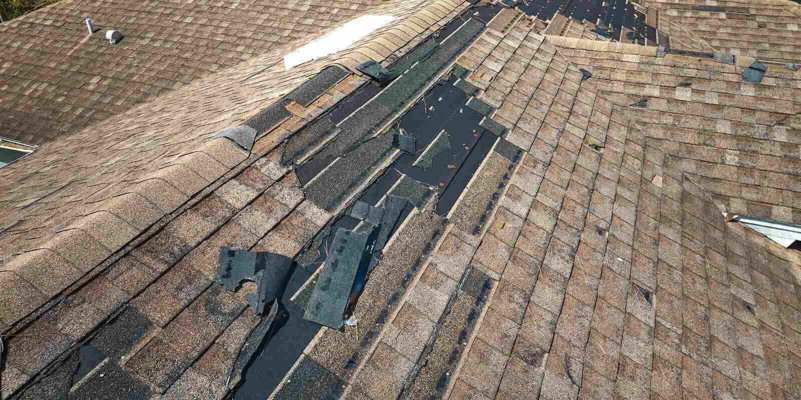 damaged house roof with missing shingles after hurricane Ian in Florida - Roof replacement