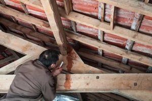 man inspecting the damaged roof