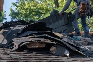 roofers removing old material from a house in preparation for storm damage repair