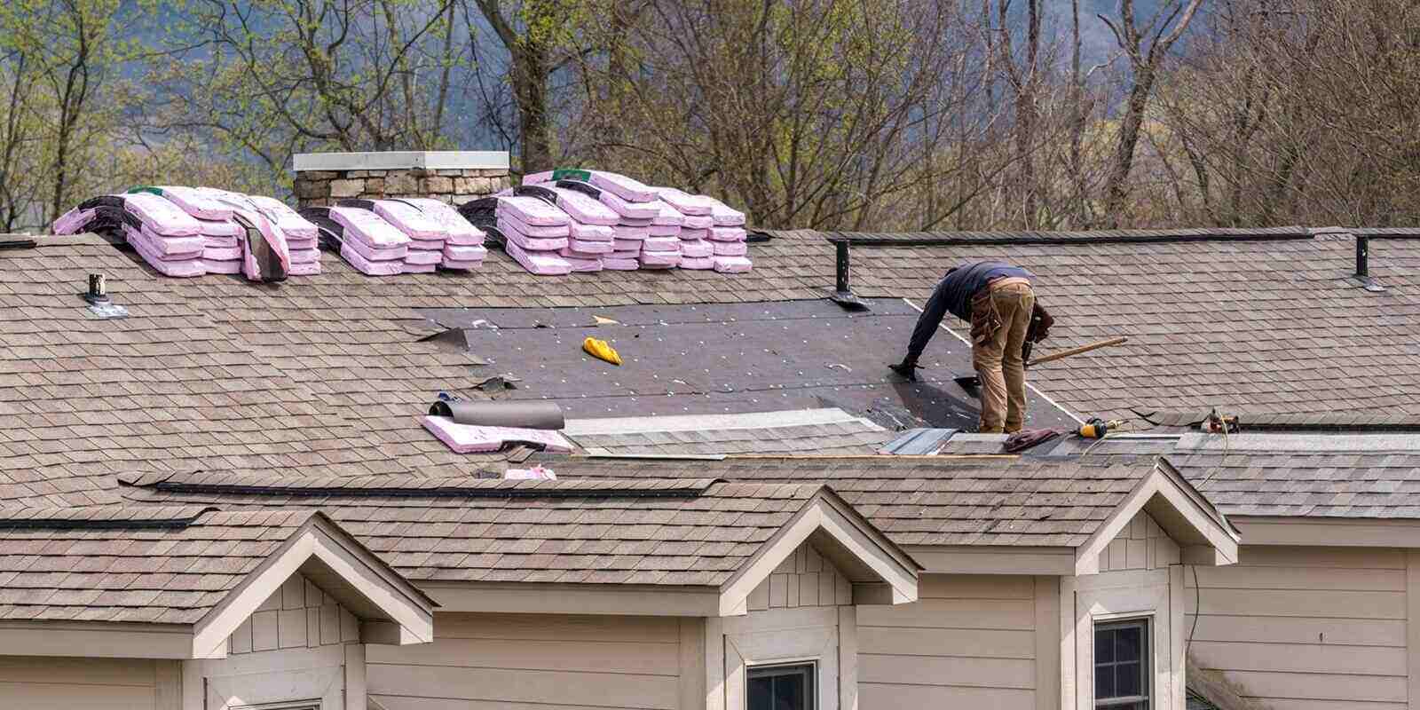 roofing contractor removing the old tiles before replacing with new shingles on a townhouse roof