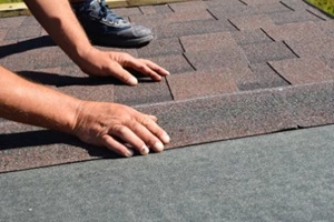 roofing contractor lay asphalt shingles tiles on house rooftop